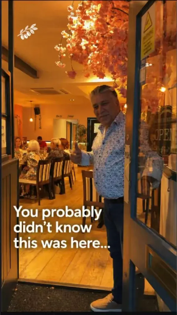 Still from the reel: the owner at the restaurant door giving a thumbs up, diners behind him under blossom decorations, with the caption You probably didn't know this was here.